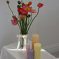 Arrangement of fluted pillar candles shown in pastel pink, purple, yellow and orange colours.