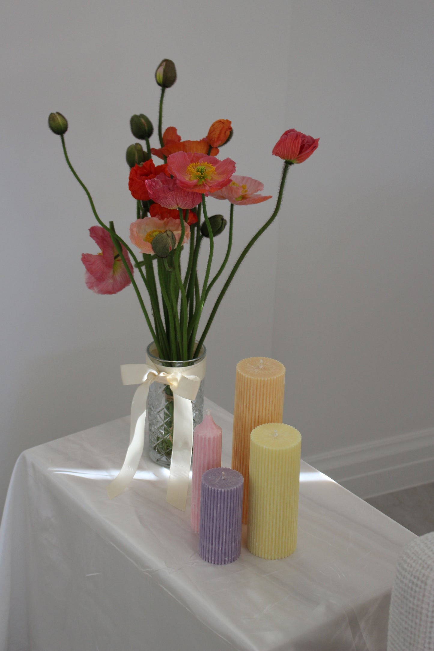 Arrangement of fluted pillar candles shown in pastel pink, purple, yellow and orange colours.