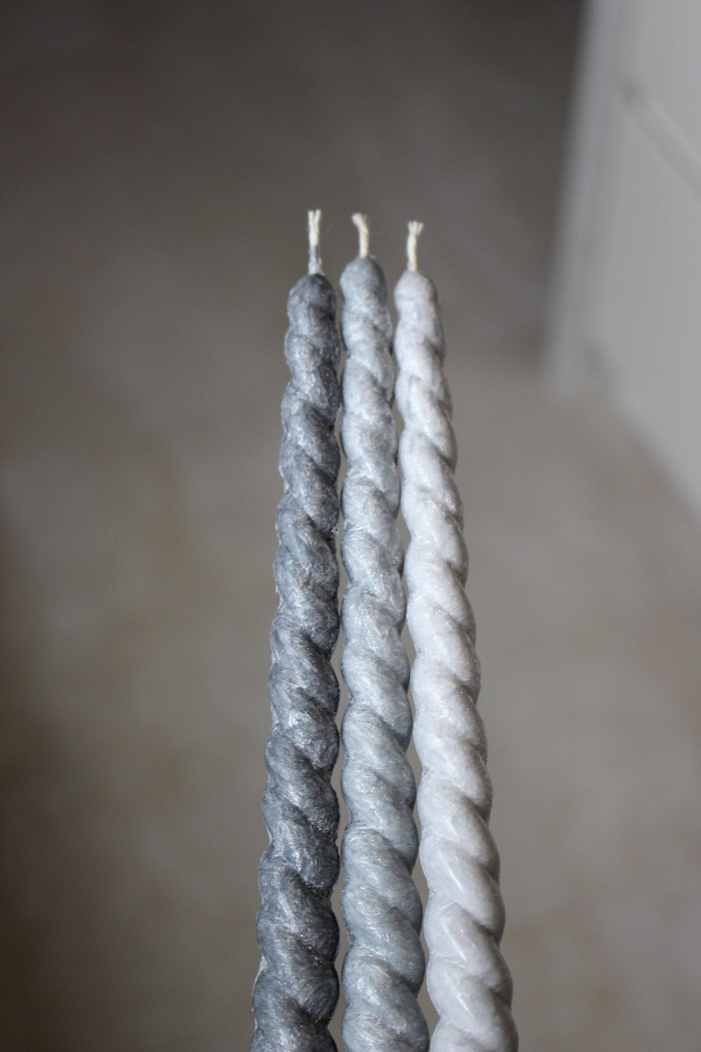 Twisty Ariel taper candles in three shades of grey shown together.