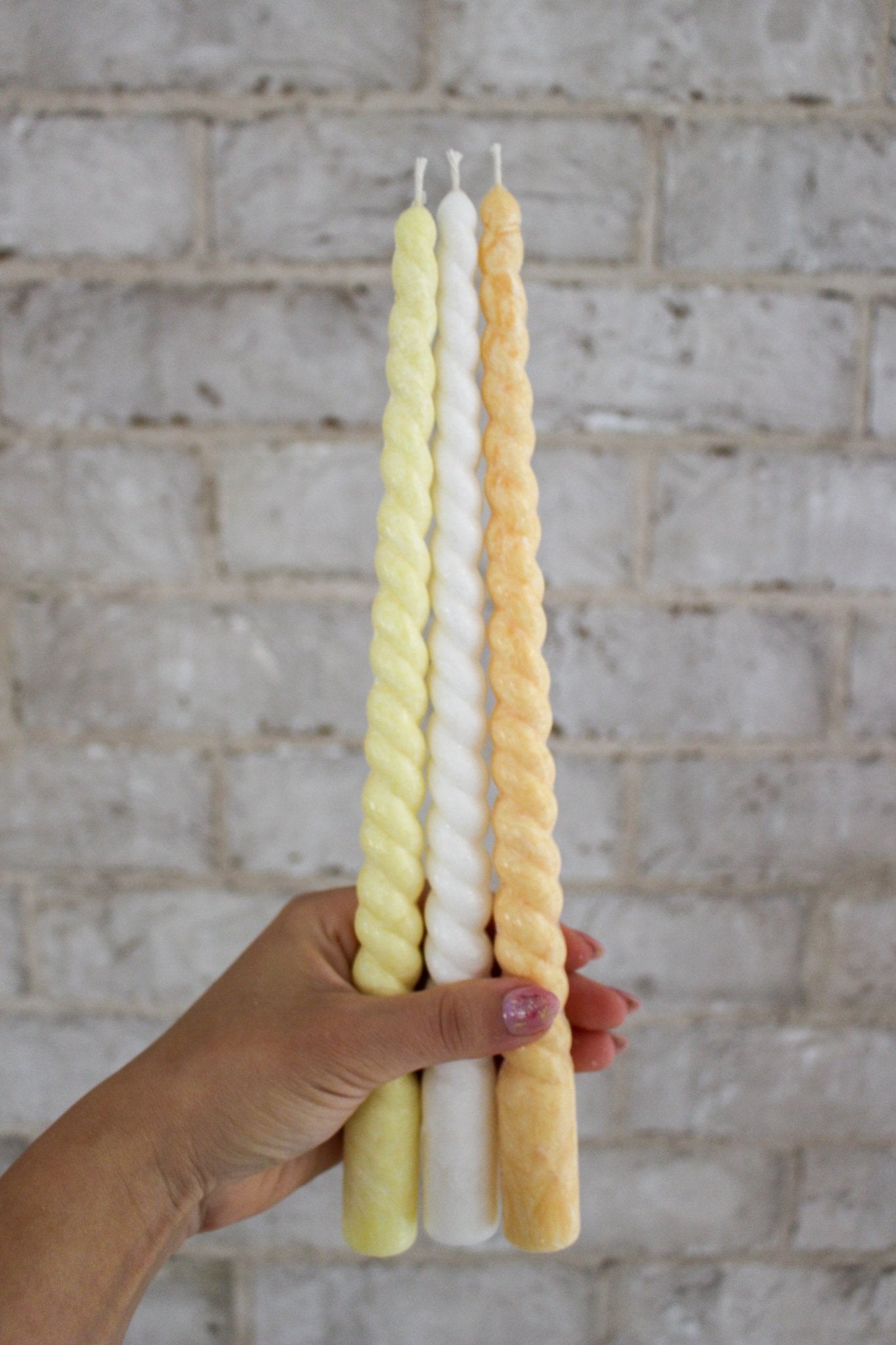 Twisty Ariel taper candles in Frangipani (yellow), Ivory (white) and Marigold (orange) shown together.