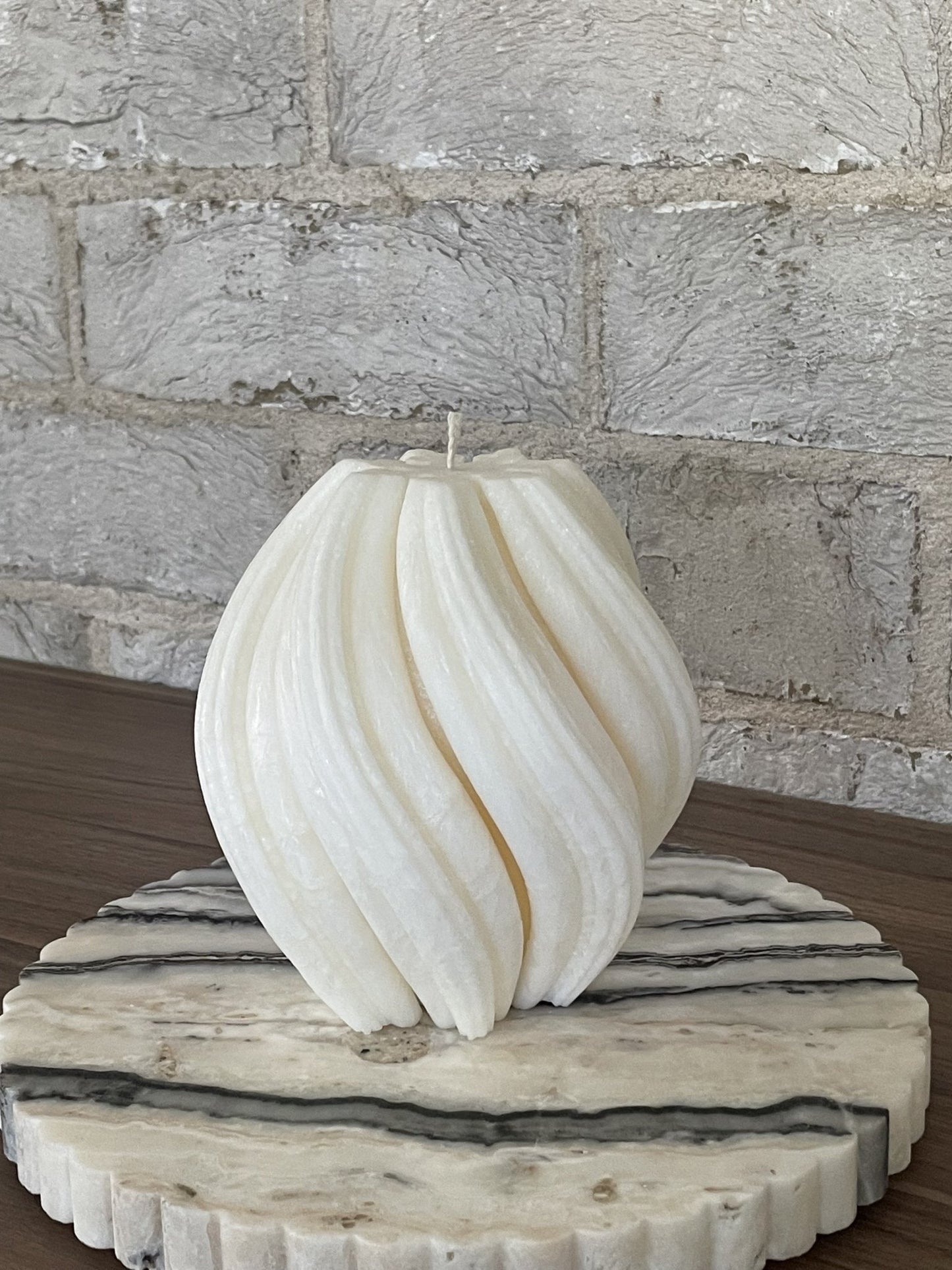 Sculptural Aurora candle in Ivory (white) colour sitting on a piece of marble.