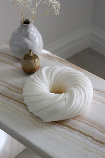 Sculptural round and curvy Lola candle in Ivory (white) colour positioned on a marble side table.