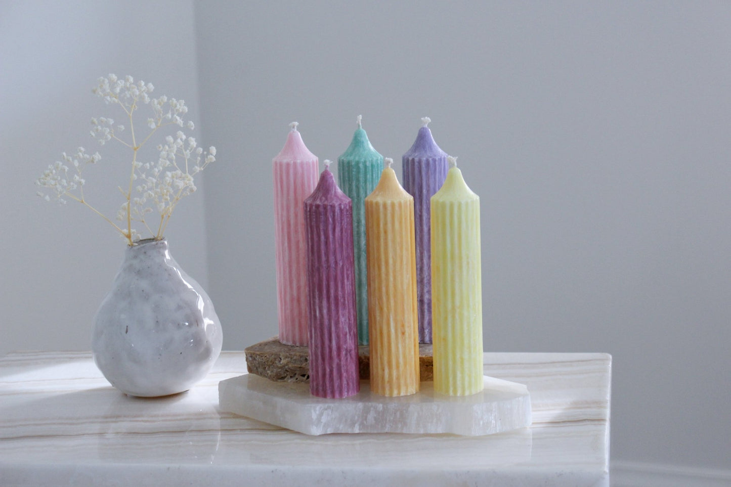 Fluted Mia pillar candles shown in pastel pink, green, lavender, cherry, orange and yellow colours.