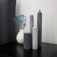 Fluted pillar candles arrangement in shades of grey on black bedside table.