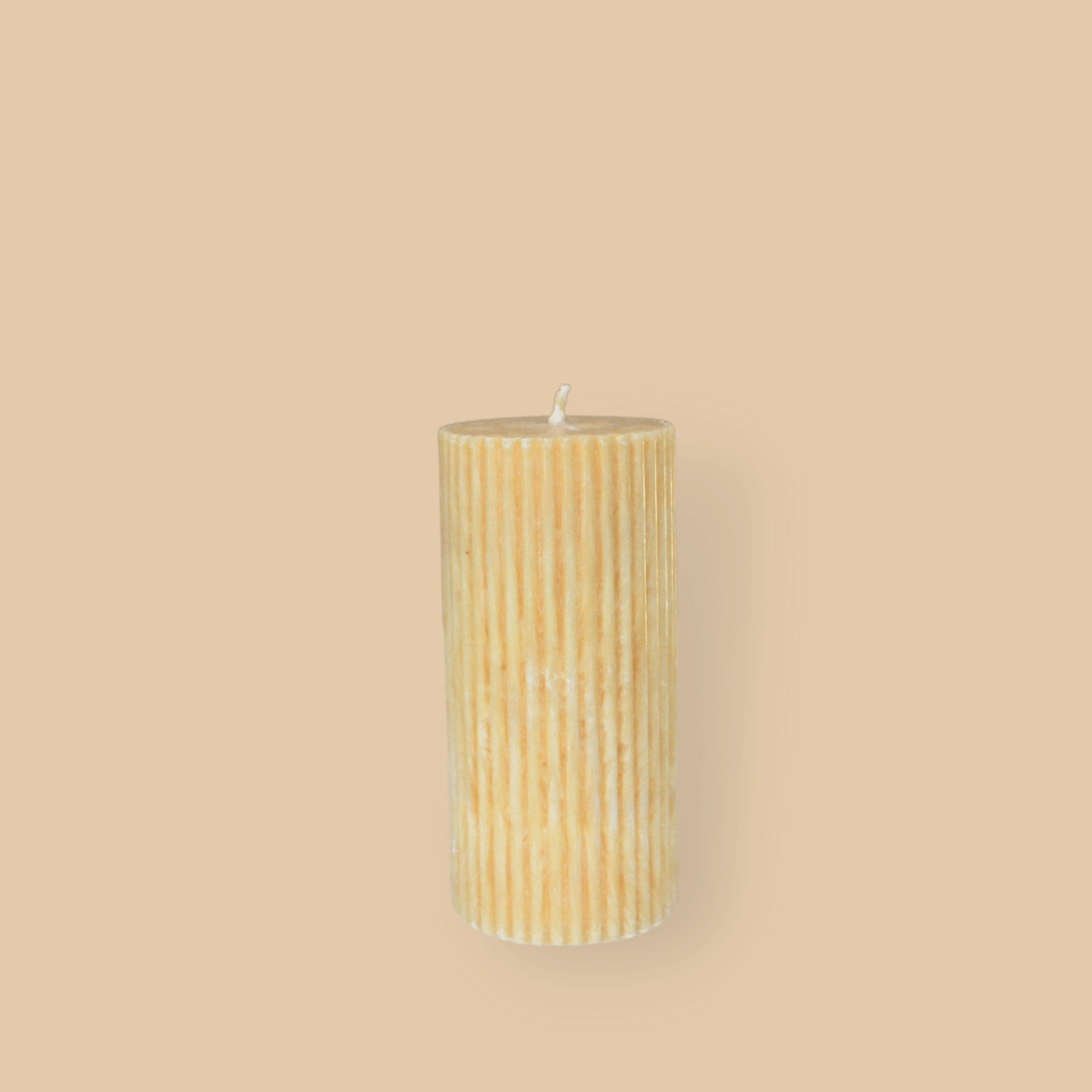 Short thick fluted pillar candle Sasha in Marigold (pastel orange) colour. This standalone pillar candle has a flat top and base.